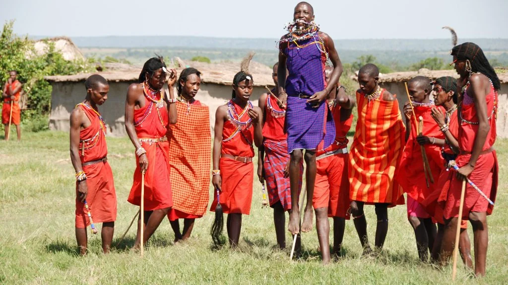 Maasai villagers in traditional beaded attire performing a dance ceremony for visitors