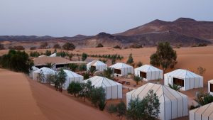 Luxury safari tents set in a desert landscape with hills in the background